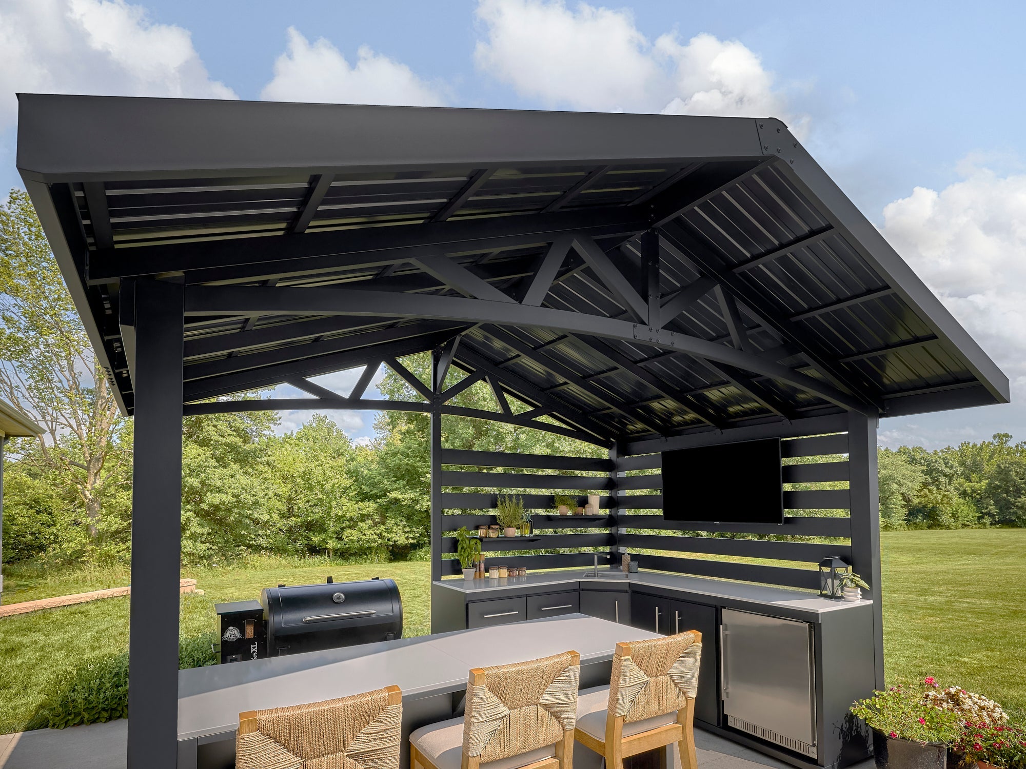 Range Outdoor Living Langston kitchen counters, bar seating, and grill in backyard.