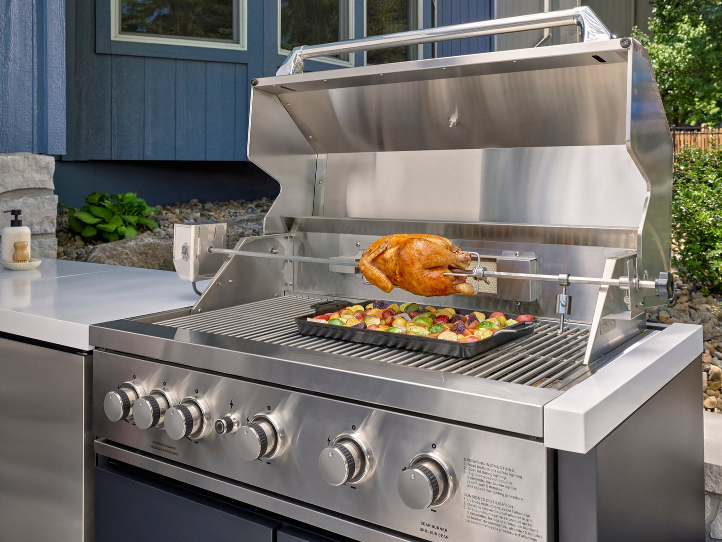 Emory built-in grill with rotisserie chicken and vegetable tray for outdoor cooking on an engineered stone countertop.