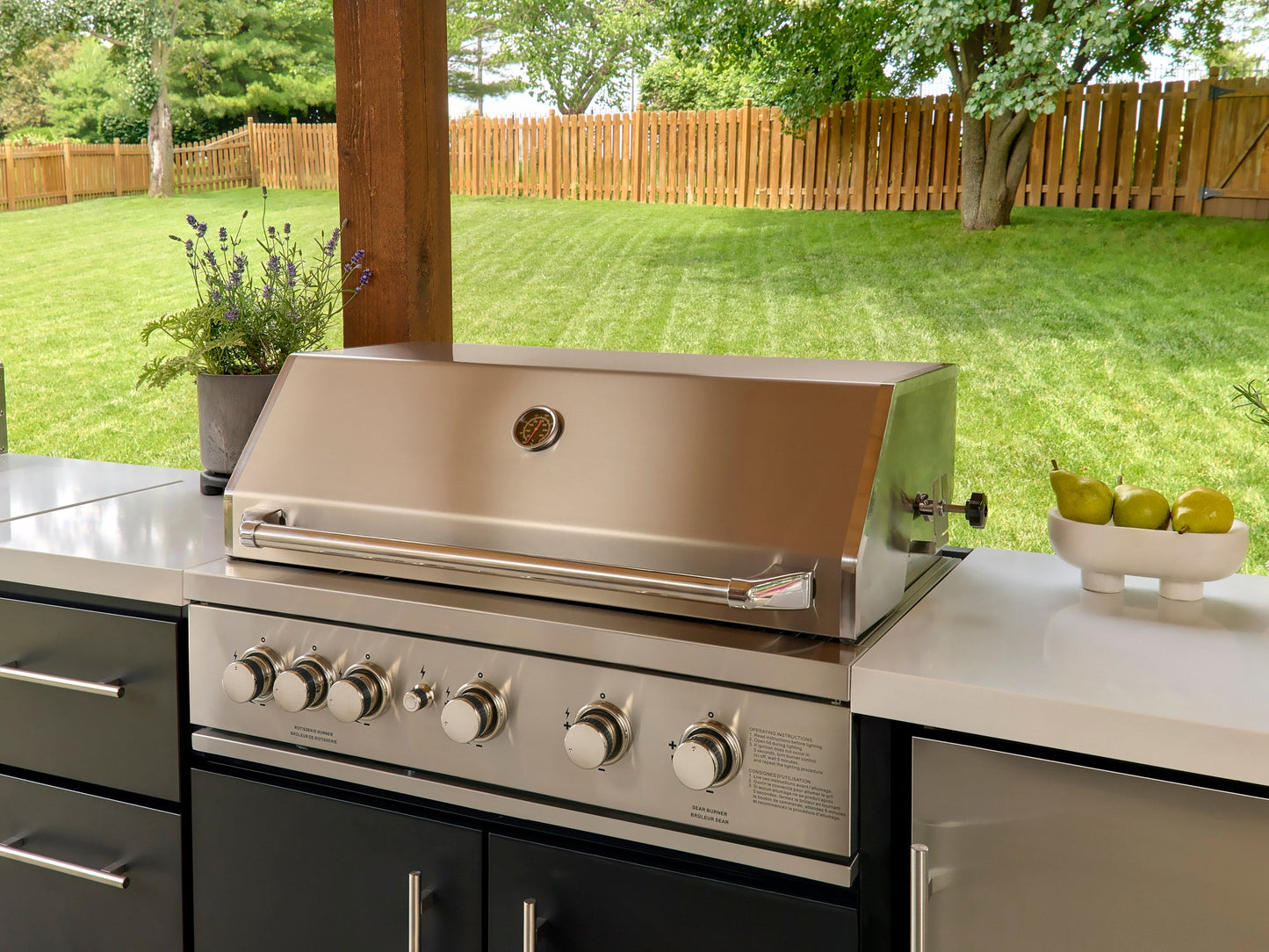 Closed built-in gas grill with temperature gauge and control knobs on countertop in Emory outdoor kitchen setting.