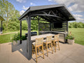 Modern steel roof covering Langston outdoor kitchen with bar seating and grill in spacious backyard setting.