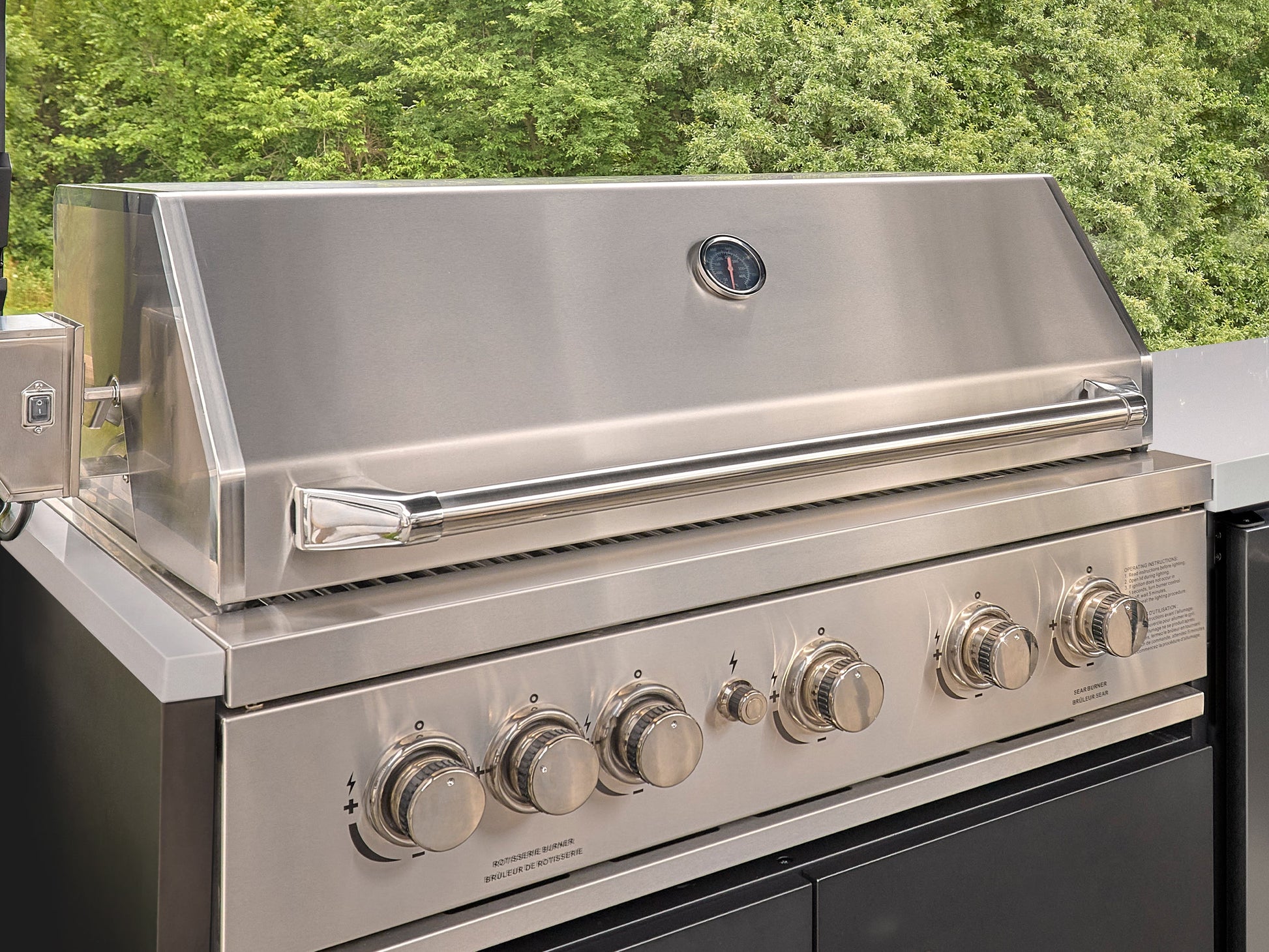 Stainless Emory steel outdoor grill with lid open, temperature gauge, chrome handle, and six control knobs on front panel.