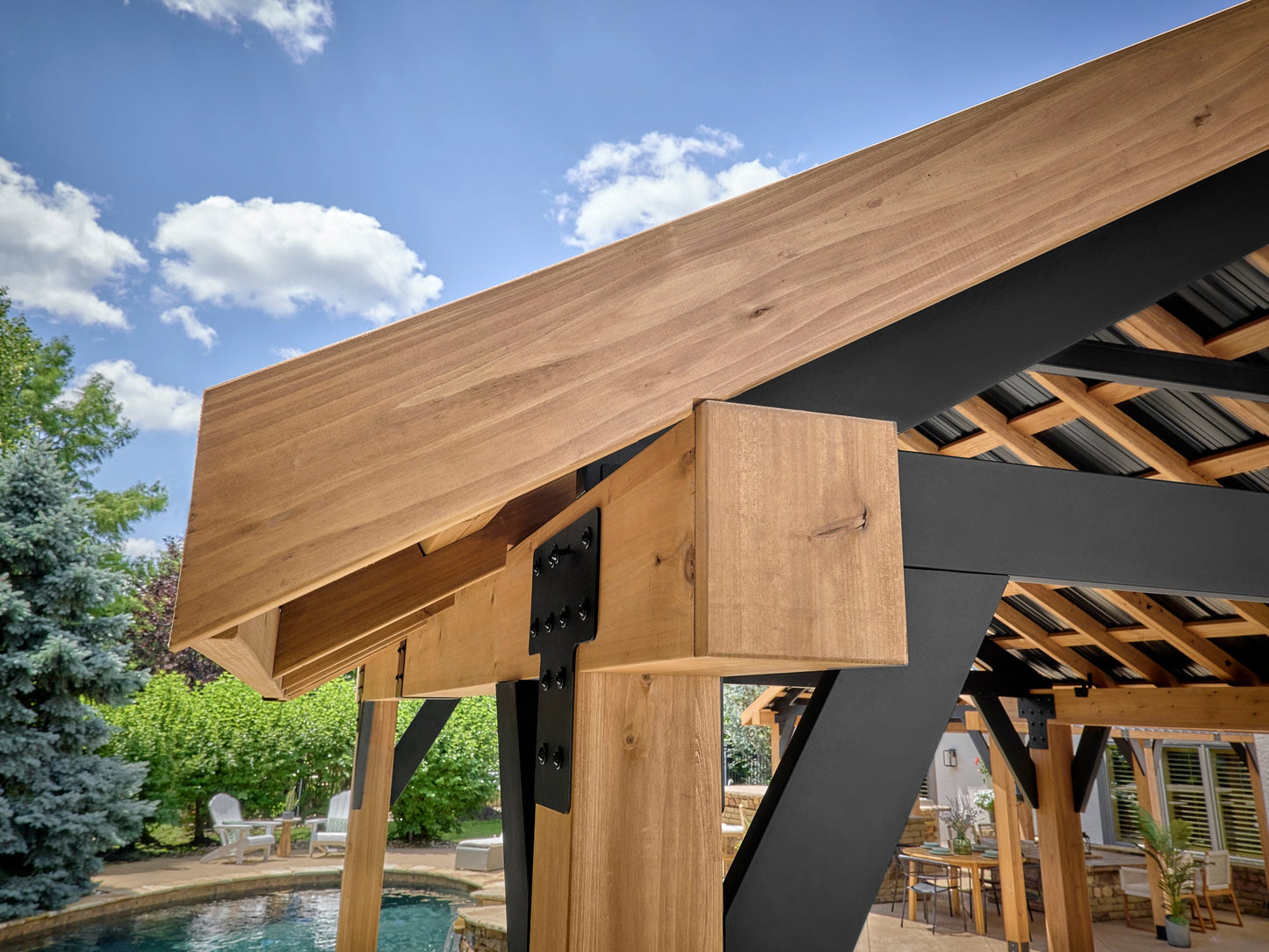 Lodge cedar steel gazebo post with black metal bracket connecting beam to vertical column under hardtop roof structure.