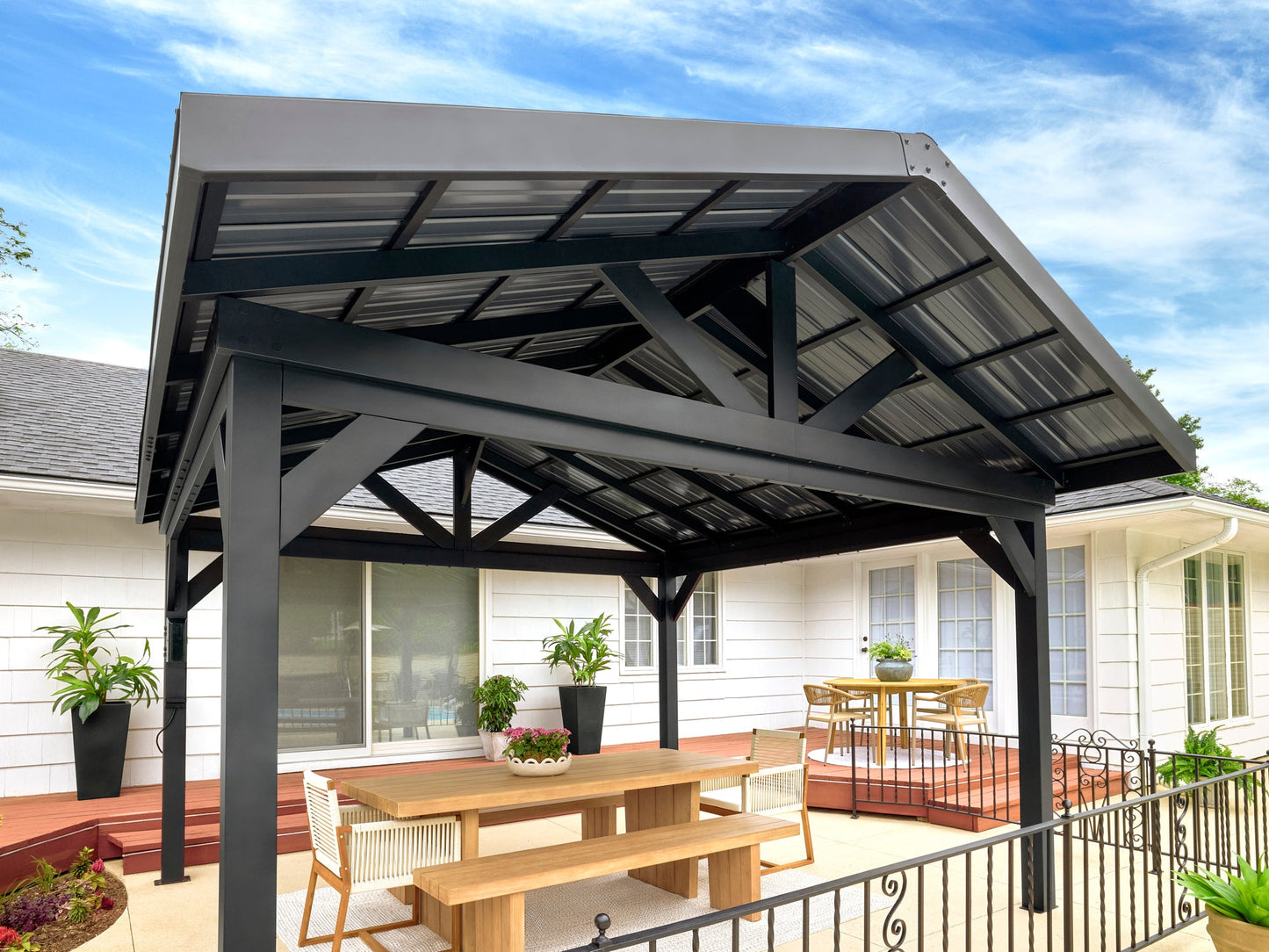 Steel gable roof gazebo with metal hardtop on wooden deck, furnished with dining table for outdoor entertaining.
